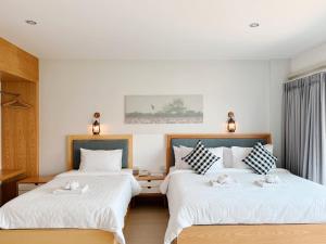 乌隆他尼普坎宁酒店的一间卧室配有两张带白色床单的床