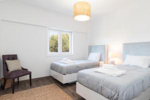 卡斯卡伊斯Cascais Duplex Apartment的一间卧室设有两张床、一把椅子和一个窗户。