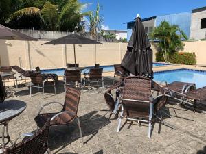 伊列乌斯Apartamento completo Ilheus的一组椅子和一把遮阳伞,位于游泳池旁