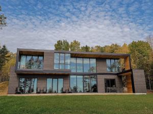 拉马巴耶Le Ruisseau: luxurious villa in Charlevoix.的草坪上设有玻璃窗户的大房子
