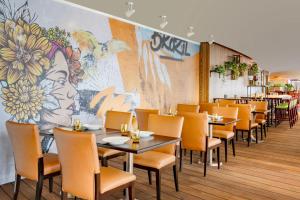 多哈多哈市中心马奎斯万豪酒店的用餐室配有桌椅和壁画