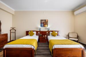 蒙特里尔Hotel Colmeia的酒店客房带两张带黄床单的床