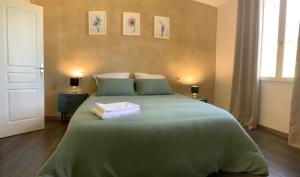 TerraubeMaison du bonheur的一间卧室配有绿床和2条毛巾