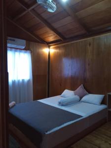 Tua PejatMentawai Bagus Local Homestay的木制客房内的一张带白色枕头的床