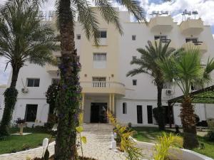 苏塞Hotel Diar Meriam的一座白色的大建筑,前面有棕榈树