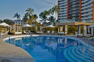巴亚尔塔港Sunset Plaza Beach Resort Puerto Vallarta All Inclusive的一个带椅子和遮阳伞的游泳池