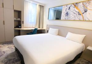 梅里尼亚克布里特酒店波尔多机场勒索雷泰尔店的一张大白色的床,位于酒店客房内