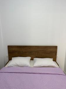 圣加利尼Maria Galini Home的一张带木制床头板和两个白色枕头的床