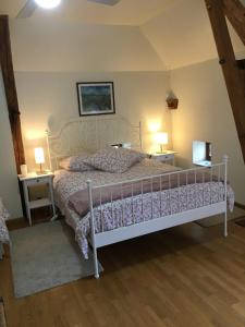 Épeigné-les-BoisLa Lézardière的卧室配有一张白色床、两张桌子和两盏灯。