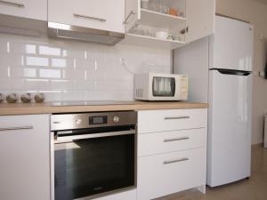 斯尼斯Cozy corner Schinias beach house的白色的厨房配备了微波炉和冰箱。