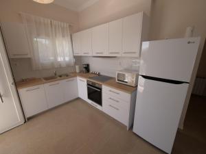 斯尼斯Cozy corner Schinias beach house的厨房配有白色橱柜和白色冰箱。