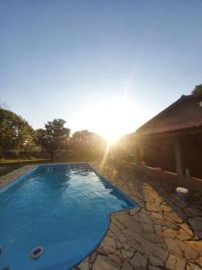 阿拉索亚巴达塞拉Chácara com Piscina的蓝色的游泳池,阳光在后面