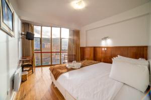 普诺Hotel Qalasaya的卧室设有白色的床和大窗户