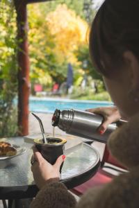 特雷利乌蜂鸟自然小屋住宿加早餐旅馆的女人把咖啡倒在桌子上杯中