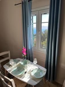 阿索斯Assos BLUE house的一张桌子,上面放有盘子和酒杯,还有一个窗口
