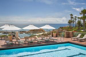 拉古纳海滩蒙太奇拉古纳海滩酒店的一个带椅子和遮阳伞的游泳池以及大海