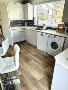 North RunctonRycroft的厨房配有白色橱柜、洗衣机和烘干机
