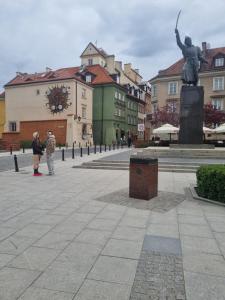华沙Old Town Pearl的两个人在广场上拍一张雕像