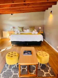 厄尔查尔坦Desierto Suites的一间卧室配有一张床、一张桌子和黄色的椅子