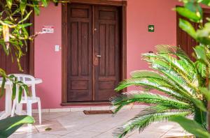 伊利亚贝拉Hotel Alemão Beach de Ilhabela的粉红色的房子,有木门和一些植物