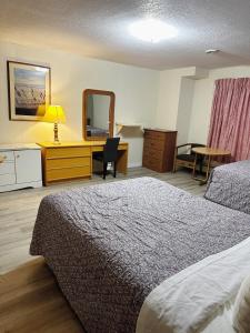 EstevanUptown Motel的酒店客房带一张床、一张书桌和一面镜子