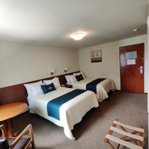 利马Hotel Carmel的酒店客房设有两张床和一张桌子。