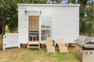 PukehinaRural Couples Retreat/Tiny House的白色的小棚子,配有两把椅子和一张桌子