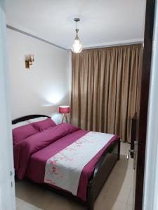 拉巴特apartment in centre ville的一间卧室配有一张带紫色床单的床和窗户。