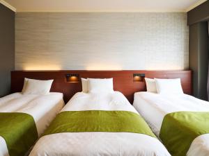 北九州Rihga Royal Hotel Kokura Fukuoka的一间设有三张绿色和白色床铺的客房