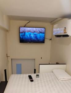 洛坤府Norm Space Hostel NST的客房设有一张床和壁挂式平面电视。