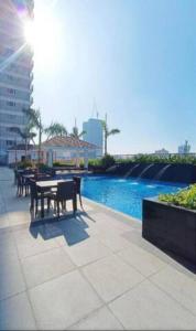 马尼拉Coast Residences Penthouse with skyline and manila bay view的池畔露台配有桌椅