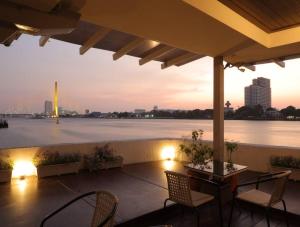 曼谷Riverfront house/Chao phraya river/Baan Rimphraya的一个带椅子的庭院,享有水景