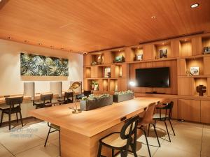 大阪First Cabin Nishi Umeda的一间会议室,配有一张大桌子和一台平面电视