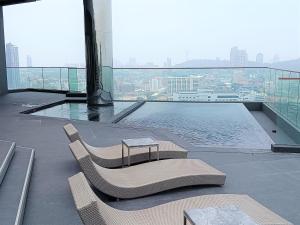芭堤雅市中心Edge Central Pattaya Lux的阳台配有两把椅子,大楼内设有一个游泳池