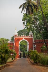 SawantwadiSawantwadi Palace Boutique Art Hotel的通往红色建筑的拱门,有棕榈树