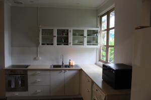 飞鱼湾Rumah Biru的厨房配有白色橱柜、水槽和窗户。