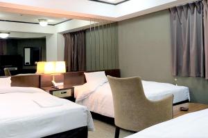尼崎市Ramada Encore by Wyndham Amagasaki的酒店客房,配有两张床和椅子
