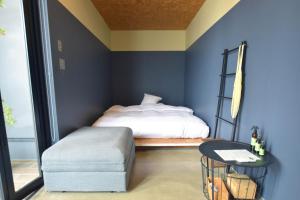 AwaTHE CHIKURA UMI BASECAMP的一间拥有蓝色墙壁的卧室、一张床和凳子