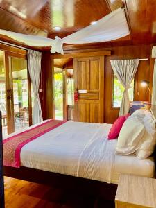 华欣泰国度假酒店的一间卧室设有一张大床、木墙和窗户。