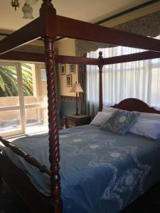 墨尔本图拉克庄园酒店的一间卧室配有一张带蓝色棉被的天蓬床