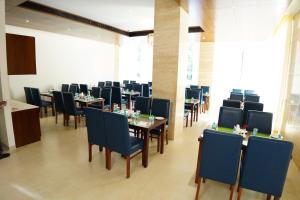 DharmastalaThe Ocean Pearl Dharmasthala Ujire的一间配备有桌子和蓝色椅子的用餐室