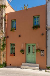 海若克利欧Sartori Concept Hotel的一座橙色的建筑,设有绿色的门和窗户