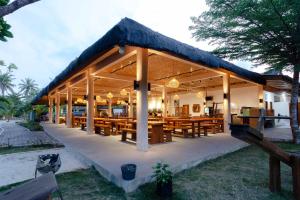 博拉科特Bintan Exotica Resort的一间设有木桌和屋顶的餐厅