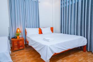 峰牙Phong Nha Magic Fingers Homestay and Spa的一间卧室配有带白色床单和橙色枕头的床。