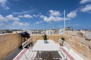 ŻejtunAuthentic Maltese 2-bedroom House with Terrace的阳台上配有白色的桌椅