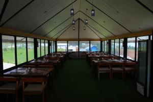 乌提The Frame Resorts Ooty的大型用餐室设有桌子和窗户。