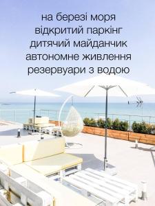 切尔诺莫斯克Klaster SeaView Hotel的露台享有海景,配有遮阳伞。