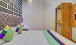 孟买Treebo Trend Prince, Mumbai的卧室配有白色的床和色彩缤纷的枕头
