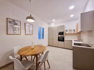 圣塞瓦斯蒂安Costa Getaria - Iberorent Apartments的厨房以及带木桌和椅子的用餐室。