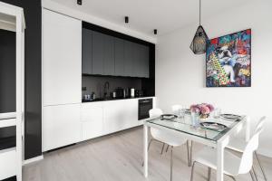 波兹南Stara Cegielnia Lake View Apartment by Renters Prestige的厨房以及带玻璃桌和白色椅子的用餐室。